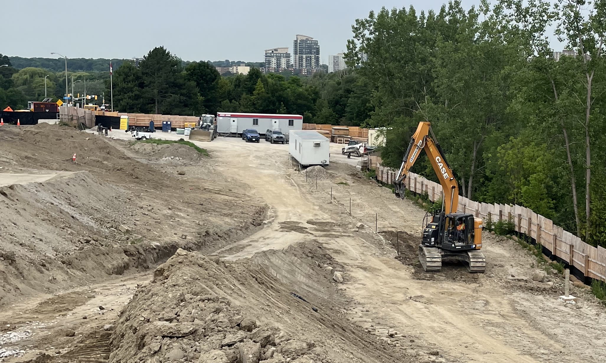 An excavator works to shape the ground at a work site for the Eglinton Crosstown West Extension.